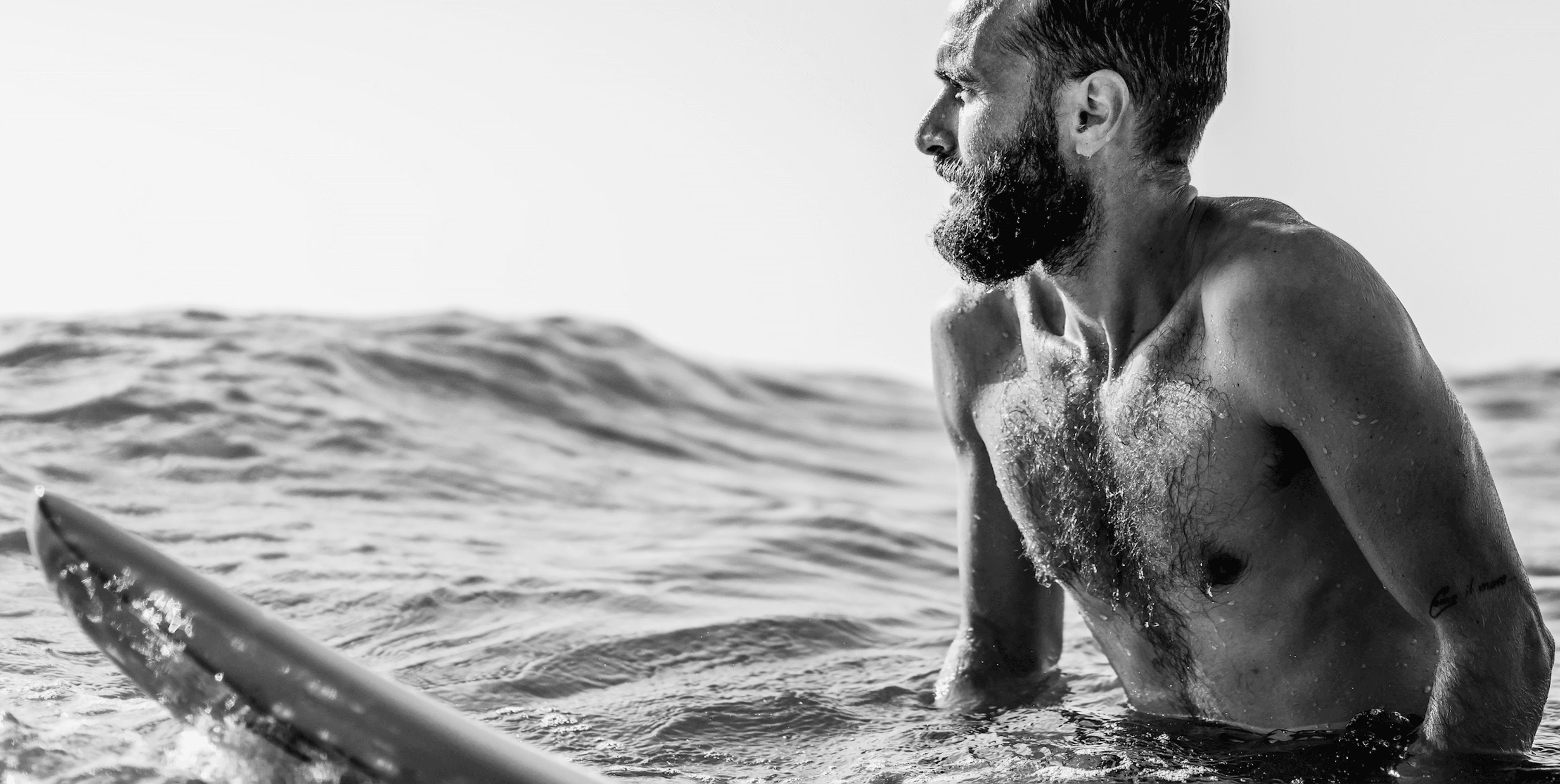 Man sitting on a surfboard in the ocean, looking toward the horizon